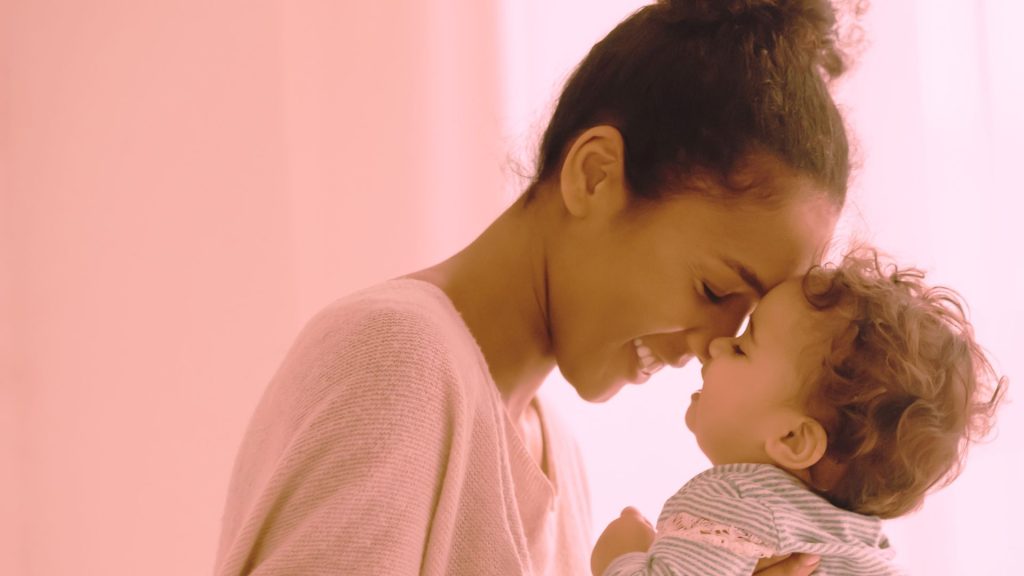 Mother is touching her forehead to her toddler's forehead.
